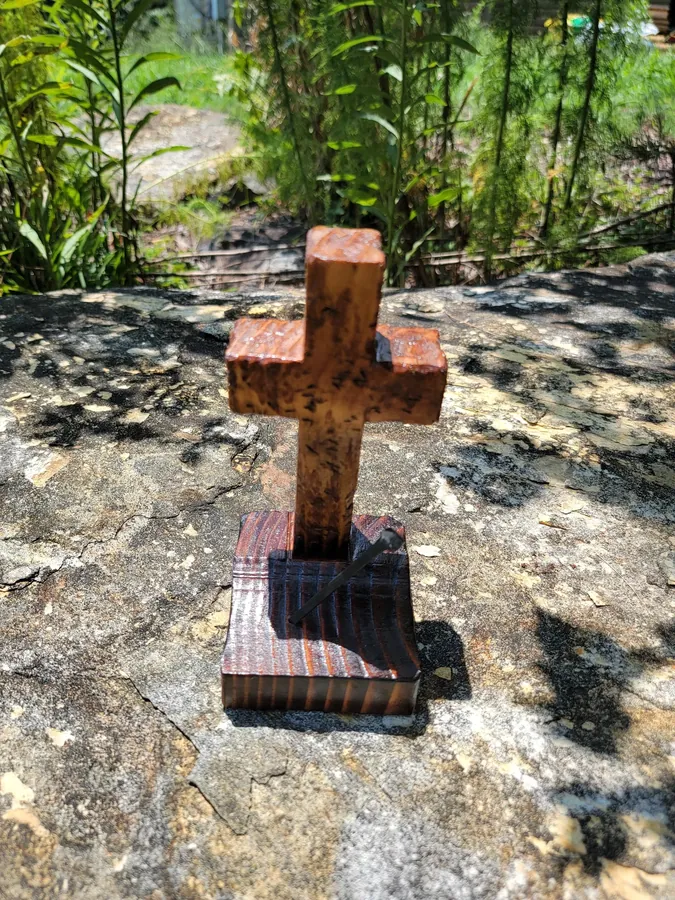 Small rustic wooden cross displayed outdoors on a rock