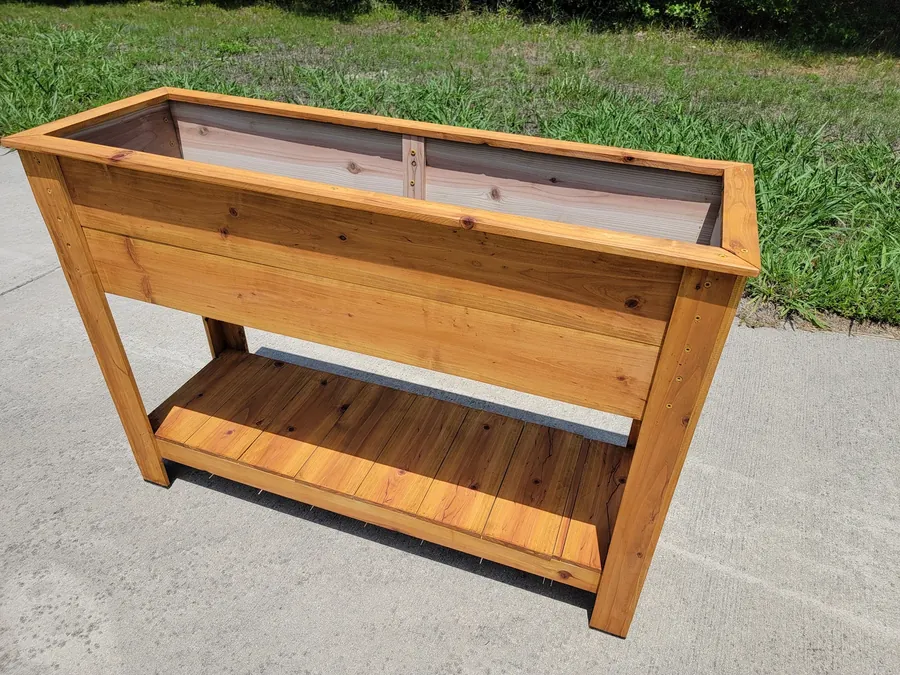 Finished raised wooden planter box with lower shelf outdoors